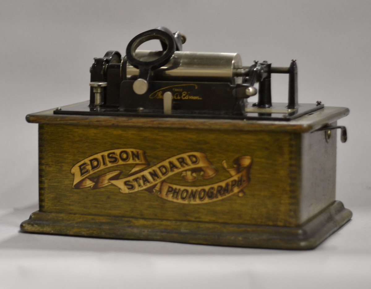 Fonograf med 3 trattar. Märkt: T A Edison, et als. Orange, NJ, USA Ljuddosa Recorder. Grönbetsad. Trattmåtten: den blanka L:535mm, Diam,311mm,B:400mm, Vikt:1,15kg. den röd/guldfärgade, L250mm,Diam:261mm, vikt:0,15kg.
Består av TM32392:1-4