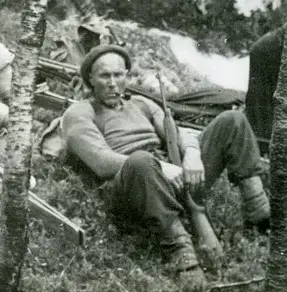 Mann som sitter med en gevær