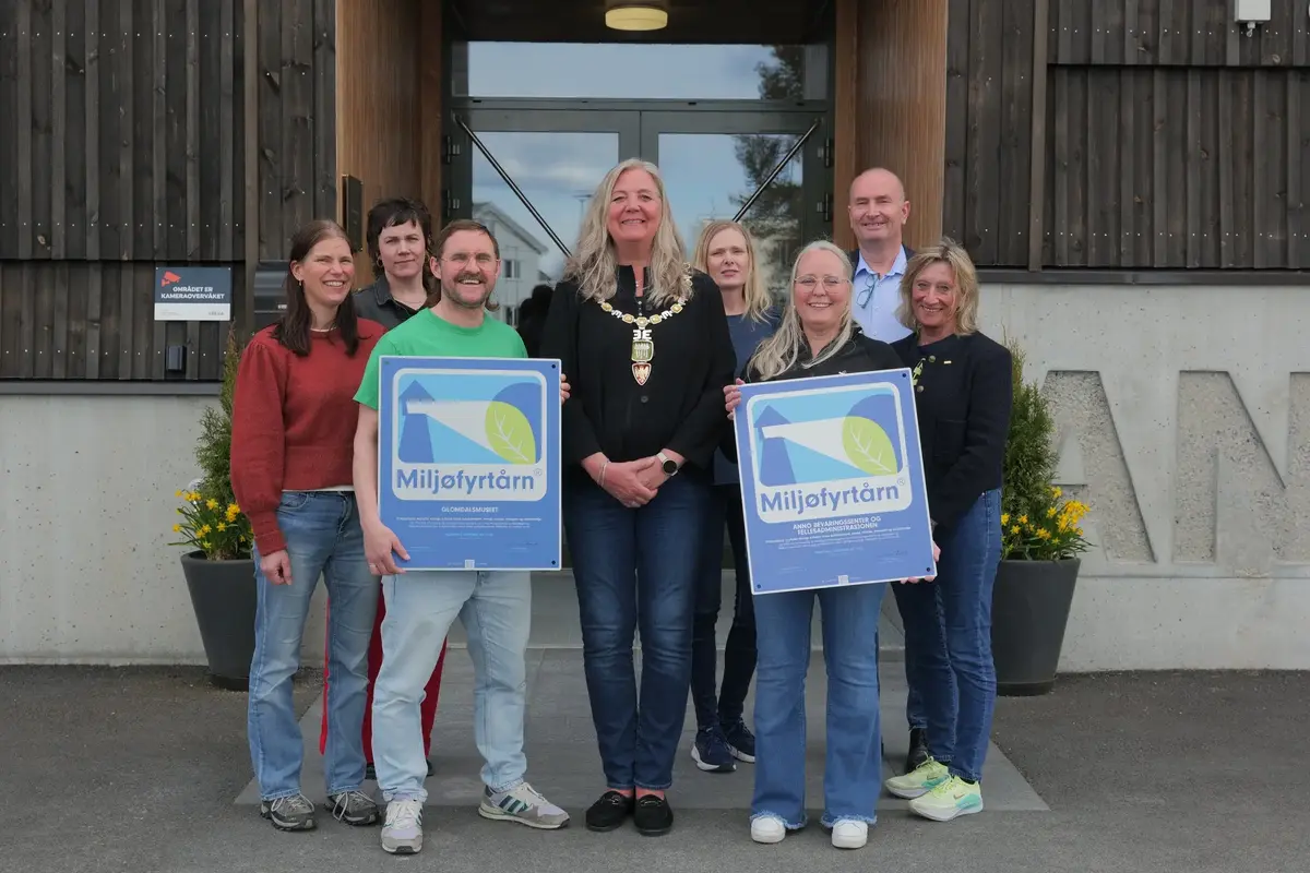 Gruppe ansatte poserer utendørs med Miljøfyrtårn-sertifikater.