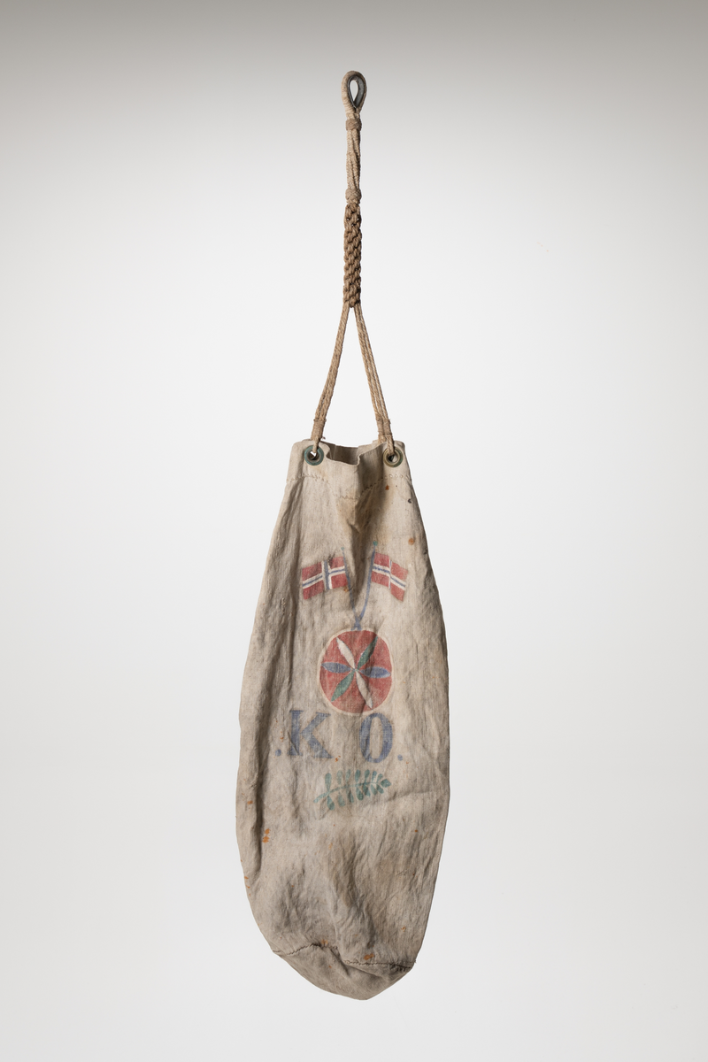 En dittybag er en liten bag eller pose  som spesielt ble brukt av sjømenn til frakt og oppbevaring av småting som sysaker, toalettsaker, etc. Pose i stoff med håndtak og dekor. To metallringer festet øverst i posen til å feste håndtaket i. Håndtak laget av tau. Tauet flettet i ulike flettverk. Tauet er festet rundt en kause. Dekor påmalt. To norske flagg over en rød sirkel med hvit kant rundt. En blomst malt på i den røde sirkelen. To grønne, to blå og to hvite blader. Under sirkelen er det malt initialene .K.O. Under et grønt blad som kan ligne på blad fra rognetre.