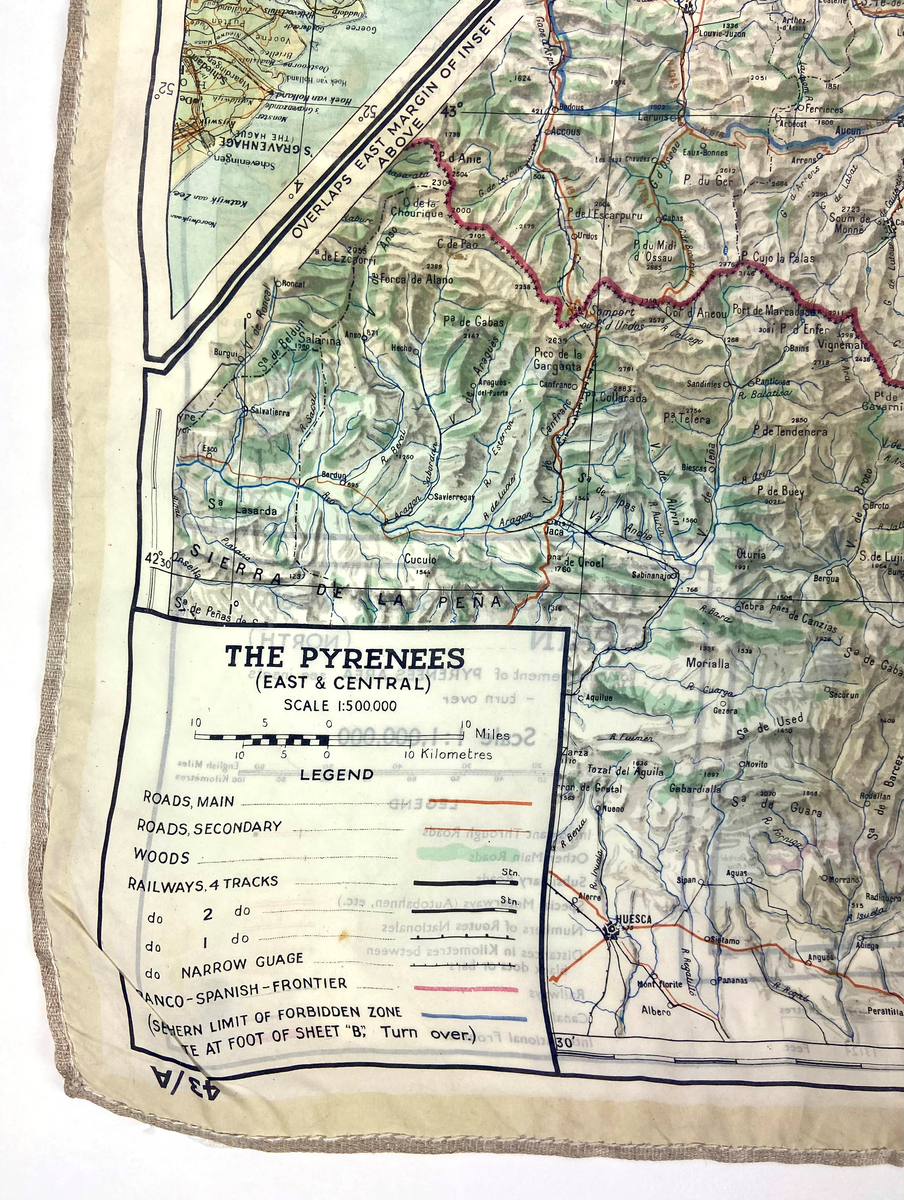 Flyktkarta tryckt på siden - över Västeuropa från Andra Världskriget. WW2. Kartan har brännhål.  Trycket är mycket detaljrikt och visar samhällen, vägar och kyrkor. Kartdetaljer i svart, vägar i rött och internationella gränser i grönt,
