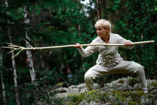 Danser som holder stav opptrer i skogen