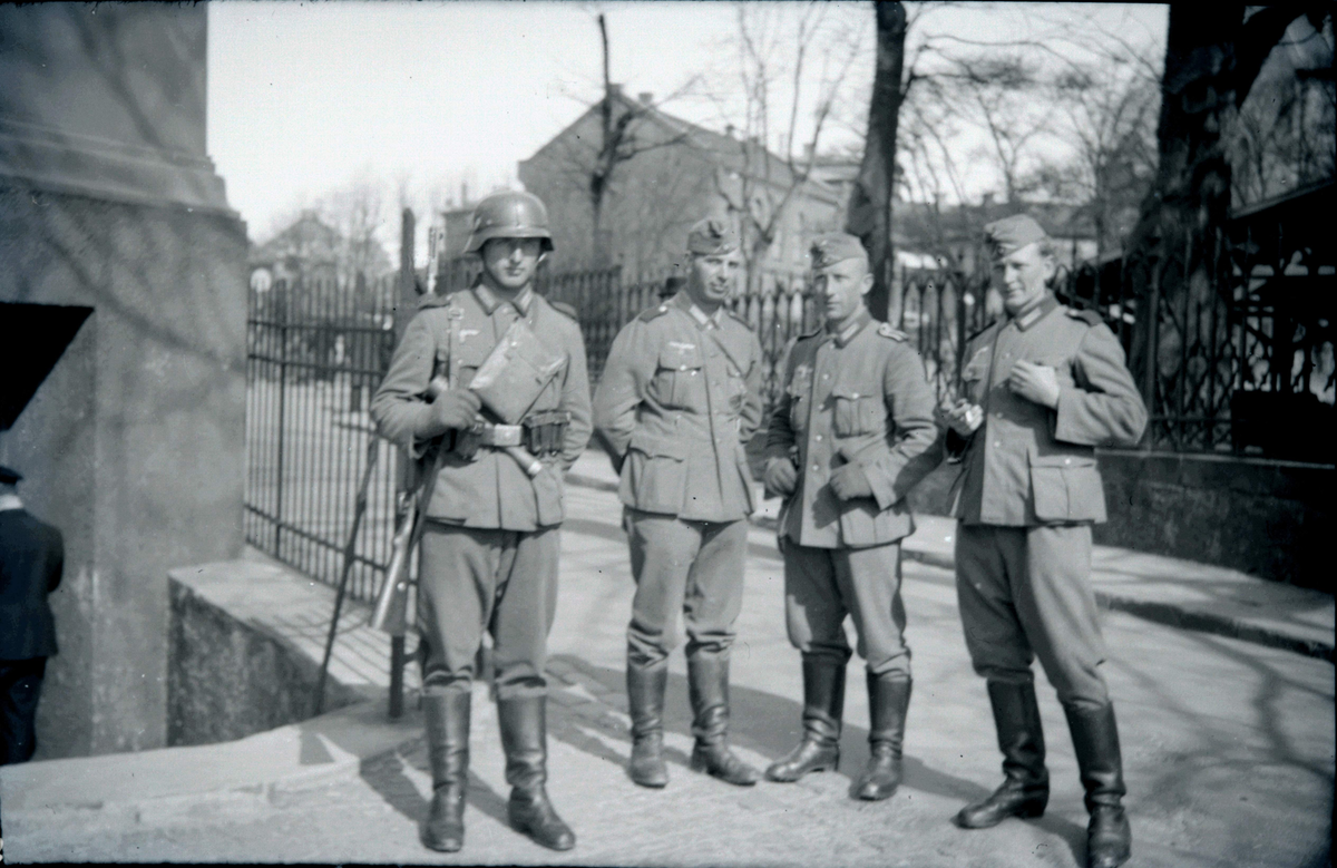 Fire menn i militæruniform med høge støvlar.