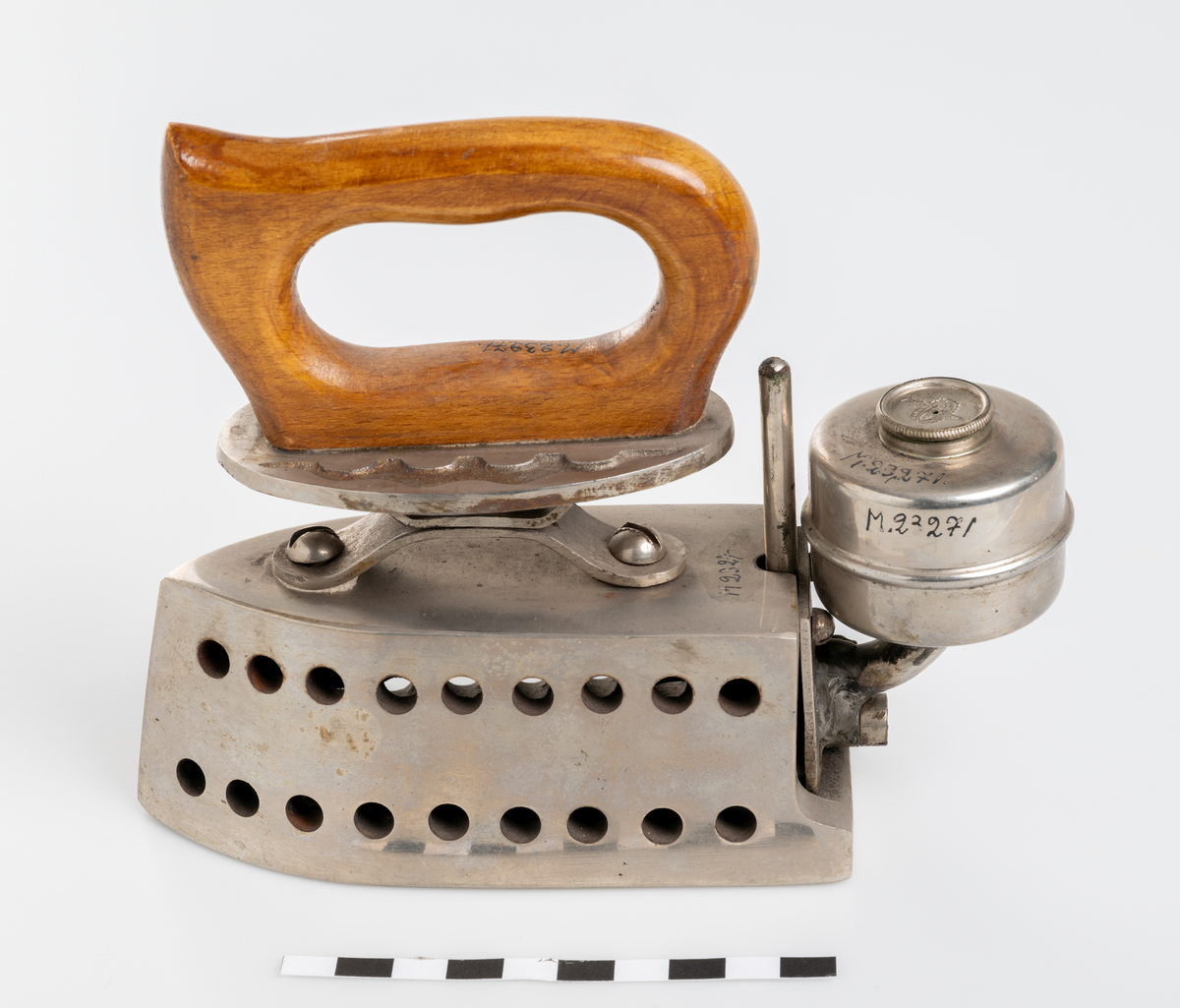 Strykjärn, pressjärn, med oljebehållare för uppvärmning. Trähandtag.

Inskrivet i huvudkatalog 1975.