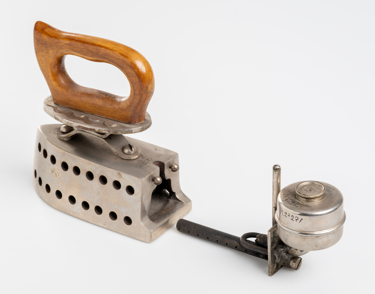 Strykjärn, pressjärn, med oljebehållare för uppvärmning. Trähandtag.

Inskrivet i huvudkatalog 1975.