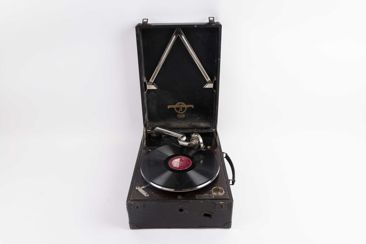 Sveivegrammofon, til å spille av 78-plater. Reise platespiller benyttet ombord i DS STORD (bg. 1913). Platespiller montert i koffert med hengslet lokk med svingbar arm av metall.