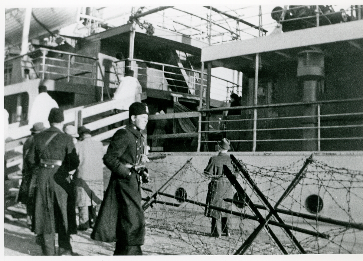 Baltutlämningen, januari 1946.
Hamnen i Trelleborg, troligtvis på morgonen, 25 januari 1946, med det sovjetiska fartyget "Beloostrov" som skulle hämta balterna.
Man har påbörjat ombordstigandet. Vid landgången står några journalister, utskickade att bevaka det hela.