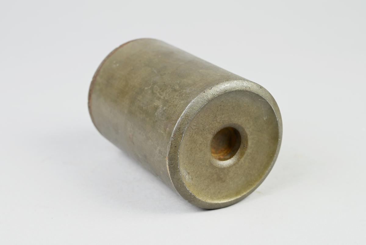 Prov på projektilhylsa. Del av tillverkningsserie. Pressad av stål från runt plåtämne vid Skultuna bruk. Märkning på provet med tejbit med notering: "H-5", samt med etikett med notering: "716".