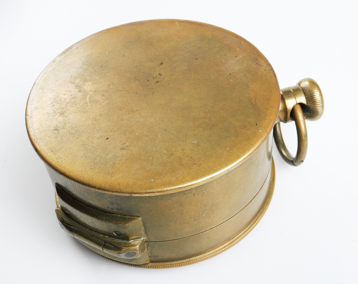 Stämpelur i mässing med öppen boett. Cylindrisk med läderfodral och axelrem. Tillhörande "nyckelskåp" i plåt med två nycklar till stämpeluret.