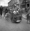 Studentfinal, 1944. 
En kvinnlig student körs iväg på cykelkärra längs Storgatan, av sina kamrater. I bakgrunden syns P.N. Perssons fastighet och 