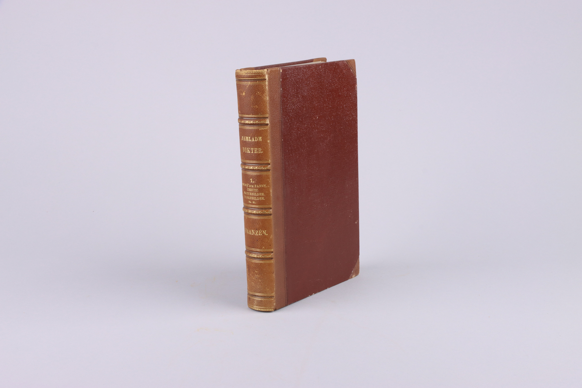 Bok, del av bokband på fyra delar. Ljusbrunt pappersband med mönsterpressad  och guldorerad rygg med upphöjda bind. Brunt pärmpapper och ljusbruna snitt. Titelsida med "Frans Michaël Franzéns samlade dikter. Första bandet".