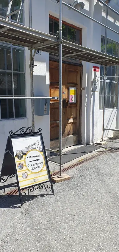 skilt som viser mot inngangsdør til museet