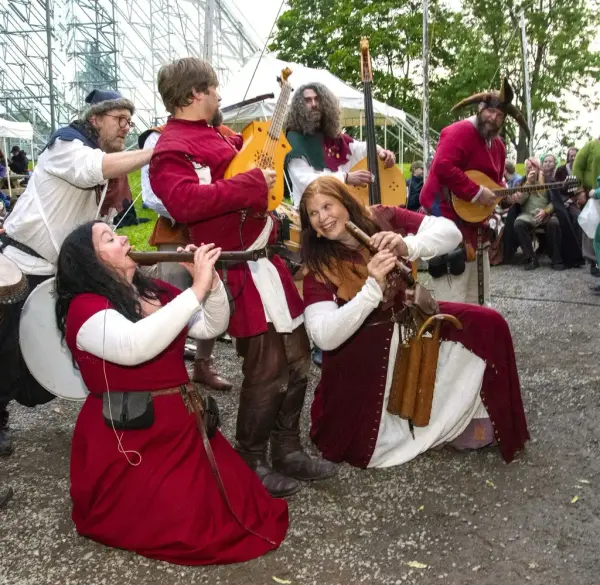 Middeladerband i røde middelalderdrakter og middelalderinstrumenter