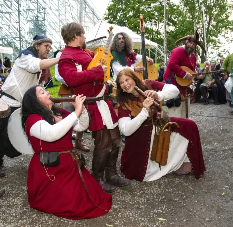 Middeladerband i røde middelalderdrakter og middelalderinstrumenter