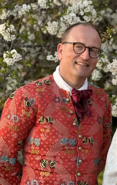 Bjørn Sverre med blomstrete drakt og blomster i bakgrunnen