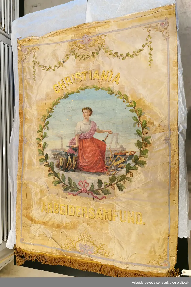Fane fra Christiania Arbeidersamfund, fanen er fra 1872 og malt av Wilhelm Krogh. Dette er forsiden, på baksiden er det et tidstyprisk bikubemotiv, men dette er ikke tatt bilde av på grunn av fanens tilstand. Fanen er for skjør til å snu eller løftes på.
