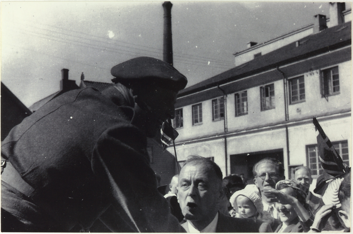 Kronprins Olav helsar på folk. Lapp på bildet i albumet: "På visitt i Stavanger og Sandnes, dro til Vatneleiren og så til Oslo. Kronprins Olav 31. juli 1945".