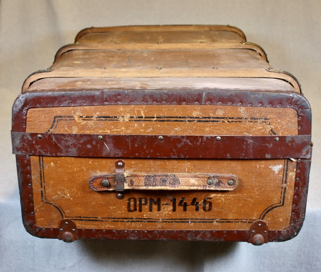 Låsbar rektangulær lysbrun koffert med metallbeslag på sidene, og trebeslag forsterket med messing. Kofferten er merket med romertall III på lokket. Hemper i lær som håndtak på hver kortside. To låser i messing. Hovedmaterialet er trolig tre. Kofferten er kledt med tekstil innvendig, og oljelerret (?) på utsiden. Enkel dekormaling