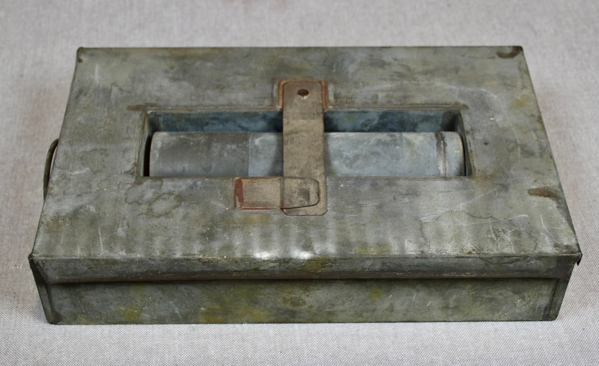 Låsbar rektangulær lysbrun koffert med metallbeslag på sidene, og trebeslag forsterket med messing. Kofferten er merket med romertall III på lokket. Hemper i lær som håndtak på hver kortside. To låser i messing. Hovedmaterialet er trolig tre. Kofferten er kledt med tekstil innvendig, og oljelerret (?) på utsiden. Enkel dekormaling