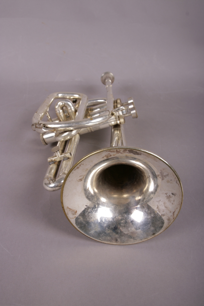 Blåseinstrument i metall med klaffer og ventiler.