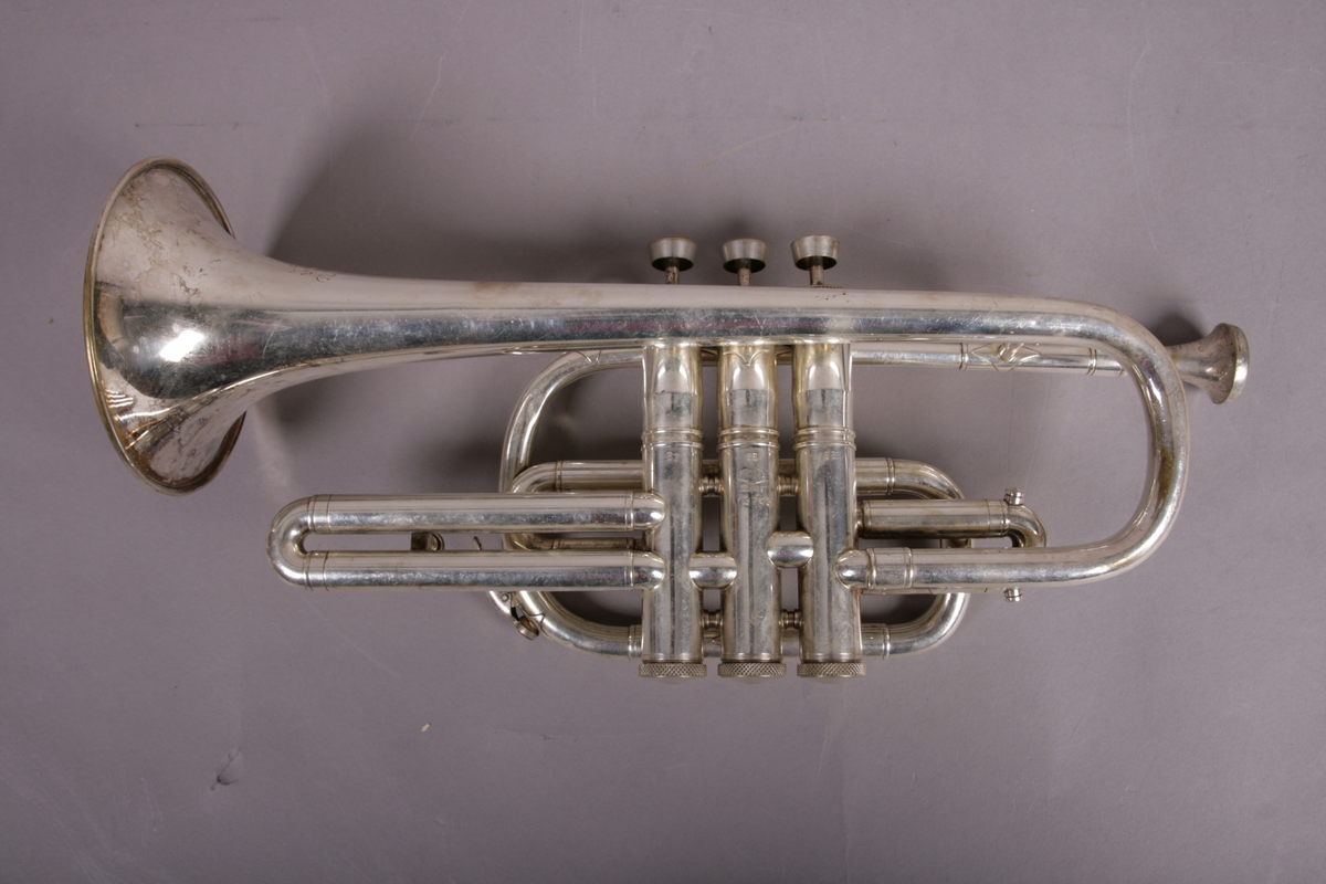 Blåseinstrument i metall med klaffer og ventiler.