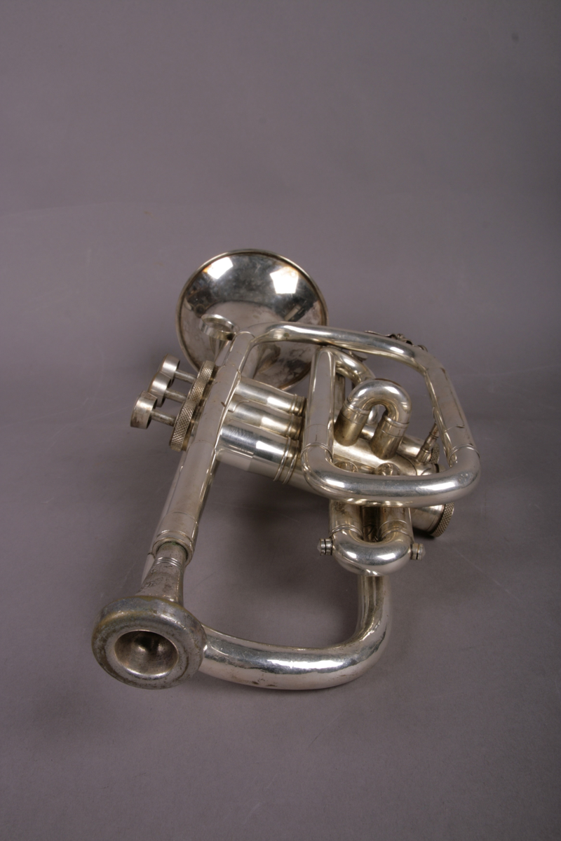 Blåseinstrument i metall med klaffer og ventiler.