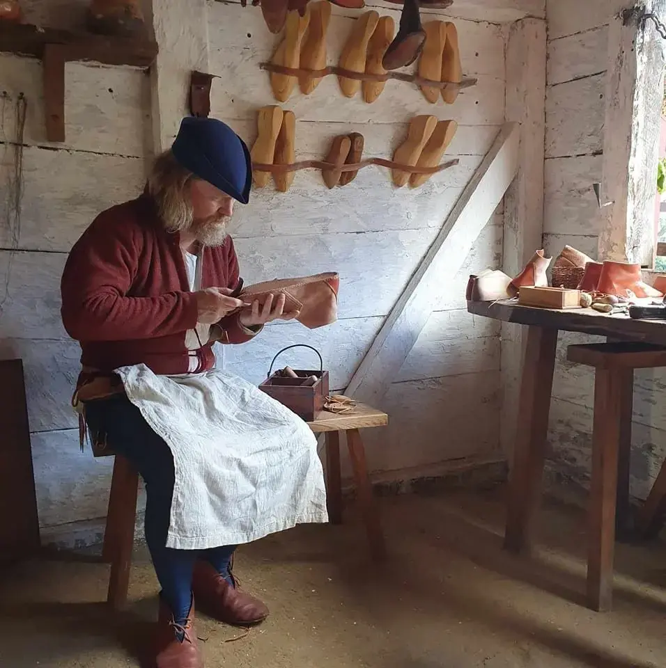 Mann i middelalderklær som lager sko