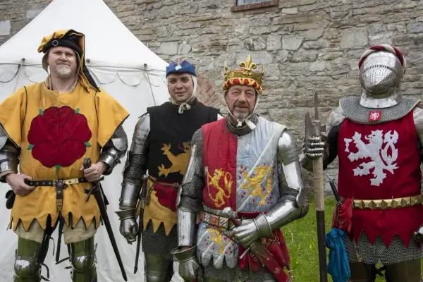 Fire menn i platerustning og fargerike surcotes