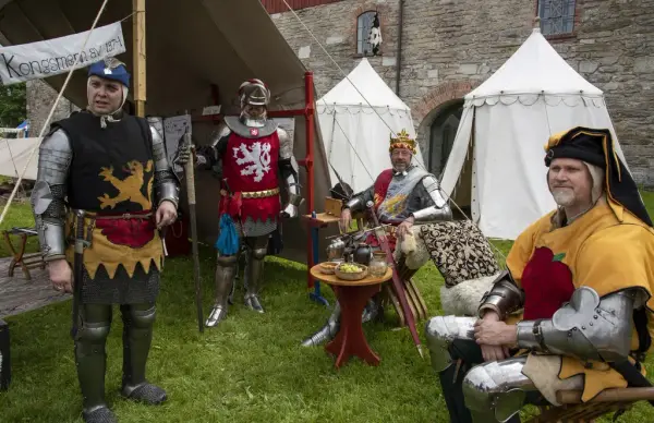 Tre menn og en konge i fargerike platerustninger