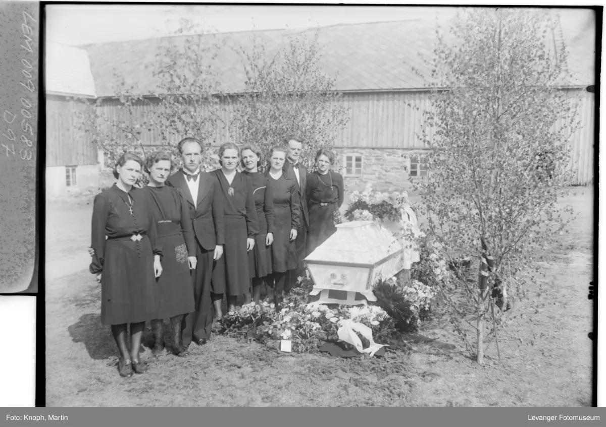 Begravelse, familien står ved kista. På gården til avdøde.