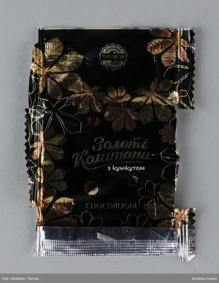 Kolorerad plåtask med lock avsedd för chokladpraliner. Asken är dekorerad med flera olika bildmotiv i blått, brunt, svart, gult och orange. Inuti asken finns 26 omslagspapper till chokladpralinerna i olika färger och mönster.
Motivet på askens lock heter "Russian warship, go...! Glory to Ukraine!". I mitten syns en ukrainsk soldat som skulle kunna vara gränsvakt. Ute på havet framför soldaten syns ett ryskt krigsskepp som kan identifieras som misilkryssaren Moskva byggd 1982. Den ukrainska soldaten är vänd mot skeppet. I sin vänstra hand håller han ett maskingevär och med den högra handen gör han en obscen gest mot fartyget.