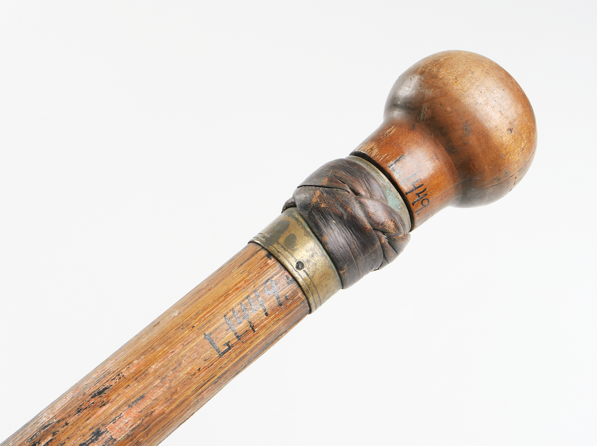 Käpp av brunmålad bambu med utdragbar värja. Rund träknopp till handtag i vilken värjan är fäst. Detaljer av mässing utmed käppen samt doppsko nedtill som avlutas i en spets. Läder virat under knoppen.
