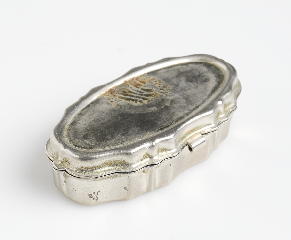 Dosa i förnicklad metall, oval form med profilerade sidor. Lock med gångjärn.