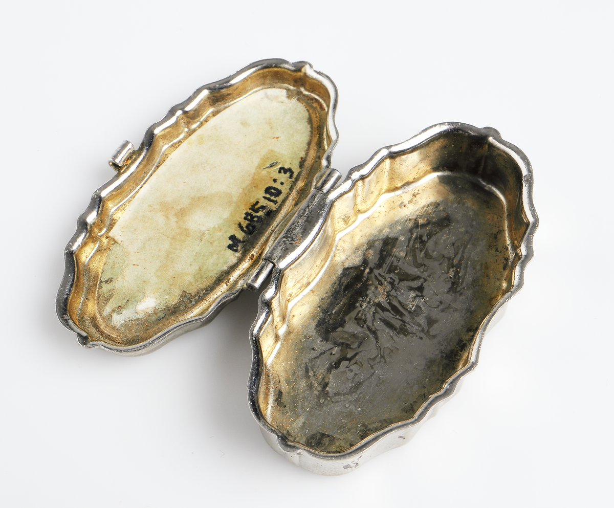 Dosa i förnicklad metall, oval form med profilerade sidor. Lock med gångjärn.