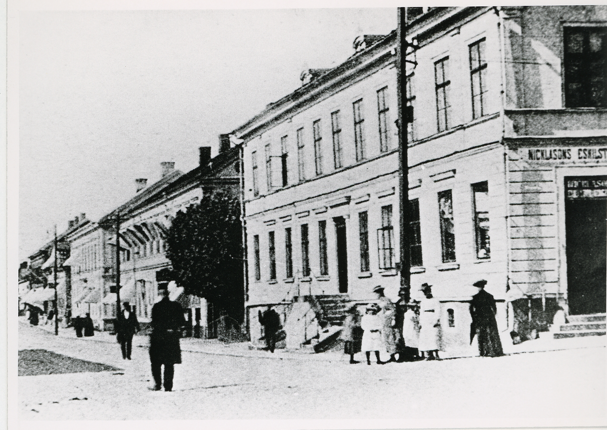 Storgatan i hörnet mot Kungsgatan, ca 1902. Till höger ser man skylten och ingången till "Nicklasons Eskilstuna-Bod", ägd av järnhandlare Johan Teofilus Nicklasson (1866-1934). En poliskonstapel patrullerar gatan.