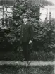 En okänd kronolänsman/landsfiskal, Kronobergs län, poserar i en trädgård, ca 1915.