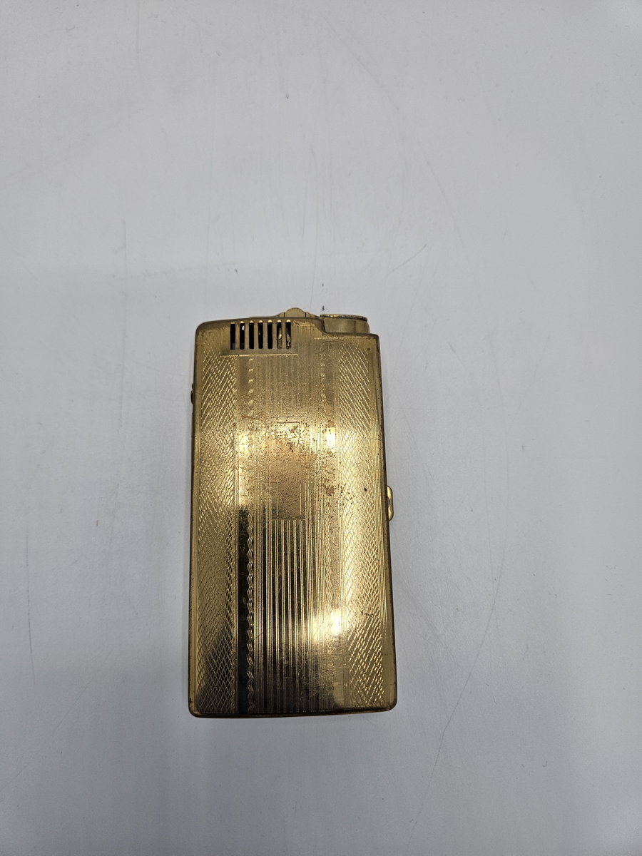 Kombinerad tändre och etui för cigaretter av metall. Troligen mässing. Guldfärgad. 