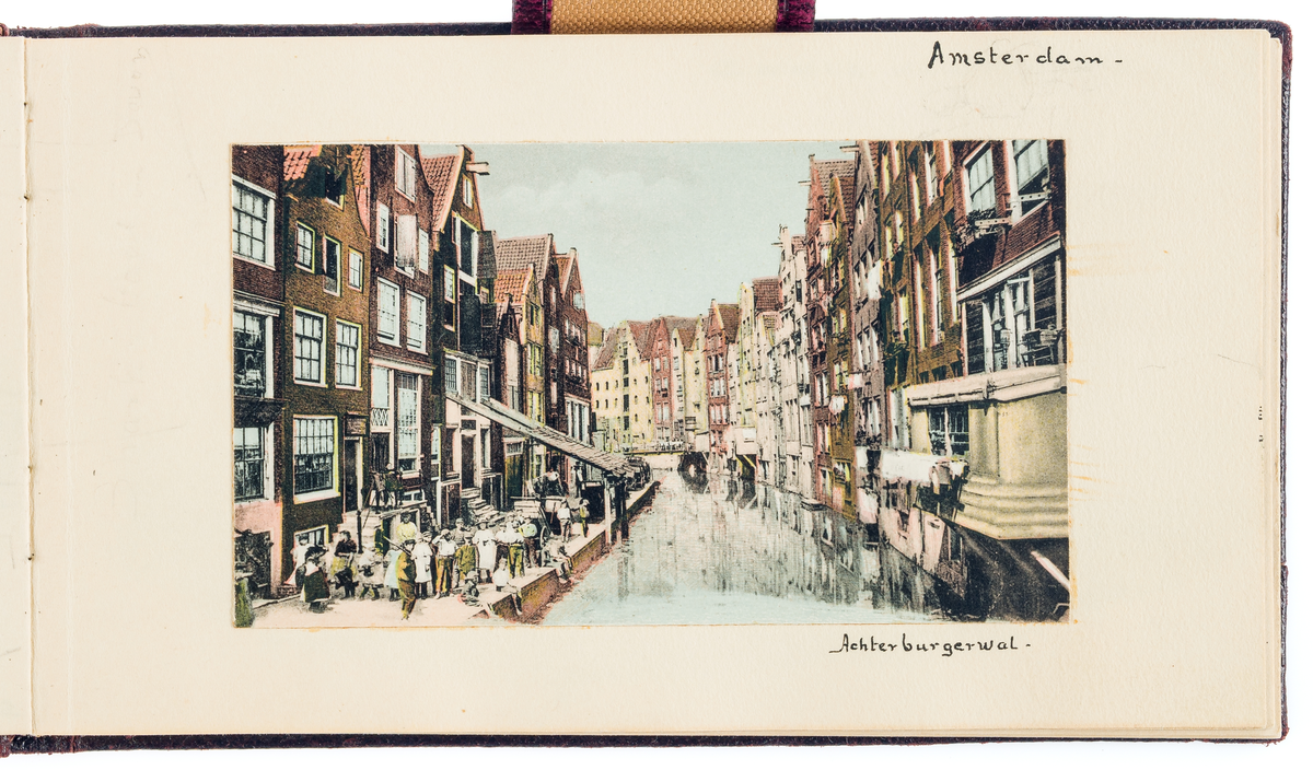 Vykortet visar stadslivet, bebyggelse vid en kanal och en gata i Amsterdam.