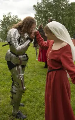 Ridder i platerustning kysser dame i middelalderdrakt på hånda