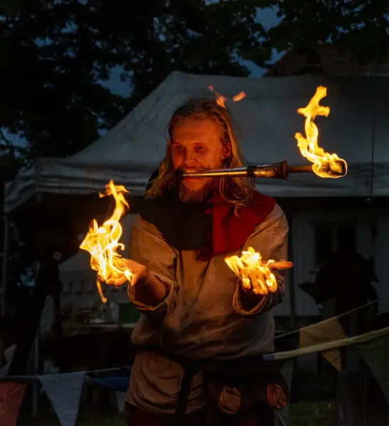 Mann som har ild i hendene og en fakkel i munnen