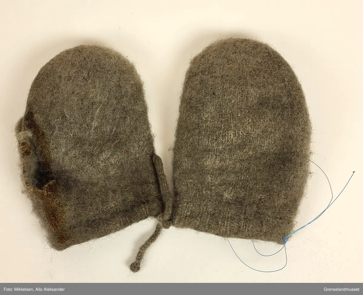 De to gjenstandene er et par grå ullvotter. Ullvottenes tilstand er ikke i god ettersom at den har flere svertede flekker og flere hull. Spesielt for votten tilhørende venstre hånd er det en stor rift fra der pekefinger ville ligge og inn over tommelen. De to vottene er festet sammen med snorer som er strikket inn i ermene.   