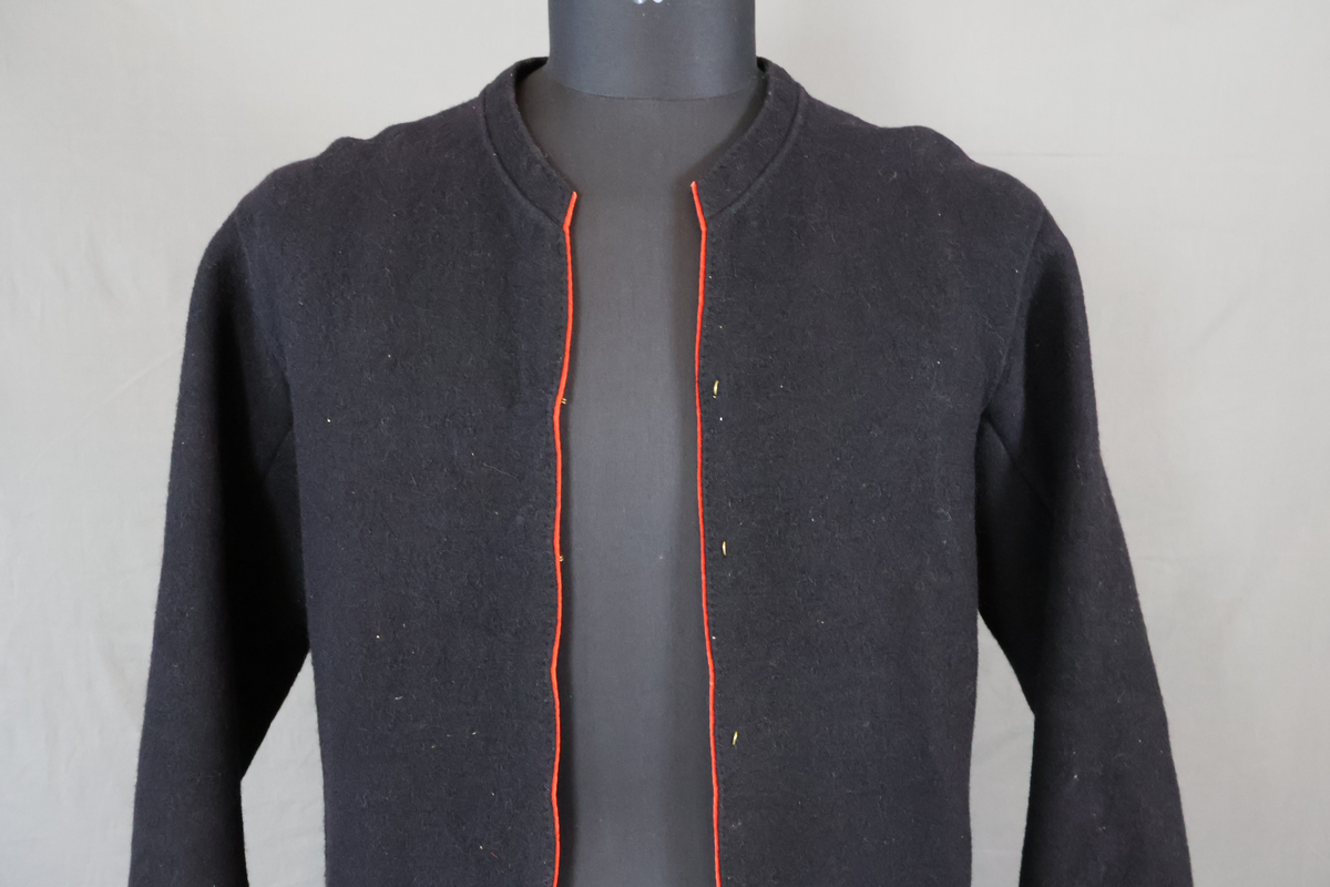 Blåtröja från Rättvik.

Blåtröjan är sydd av svart vadmal med kantning av rött kläde vid krage, framkant och ärmslut. Plagget helt ofodrat. Skörtet är skarvat. Tröjan har tre stycken hyskor på vänster sida och två stycken hakar på höger sida. Skörtet är skarvat. Sydd med en blandning av hand- och maskinsömnad.