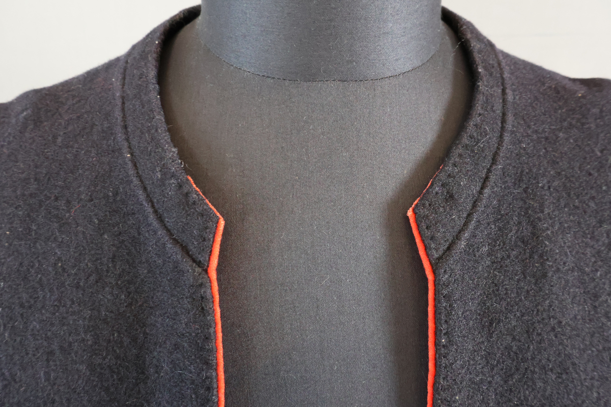 Blåtröja från Rättvik.

Blåtröjan är sydd av svart vadmal med kantning av rött kläde vid krage, framkant och ärmslut. Plagget helt ofodrat. Skörtet är skarvat. Tröjan har tre stycken hyskor på vänster sida och två stycken hakar på höger sida. Skörtet är skarvat. Sydd med en blandning av hand- och maskinsömnad.