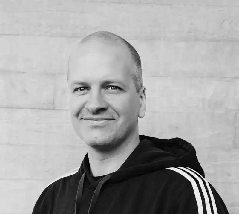 Stein Arnold Hevrøy med hettegenser framom ein betongmur