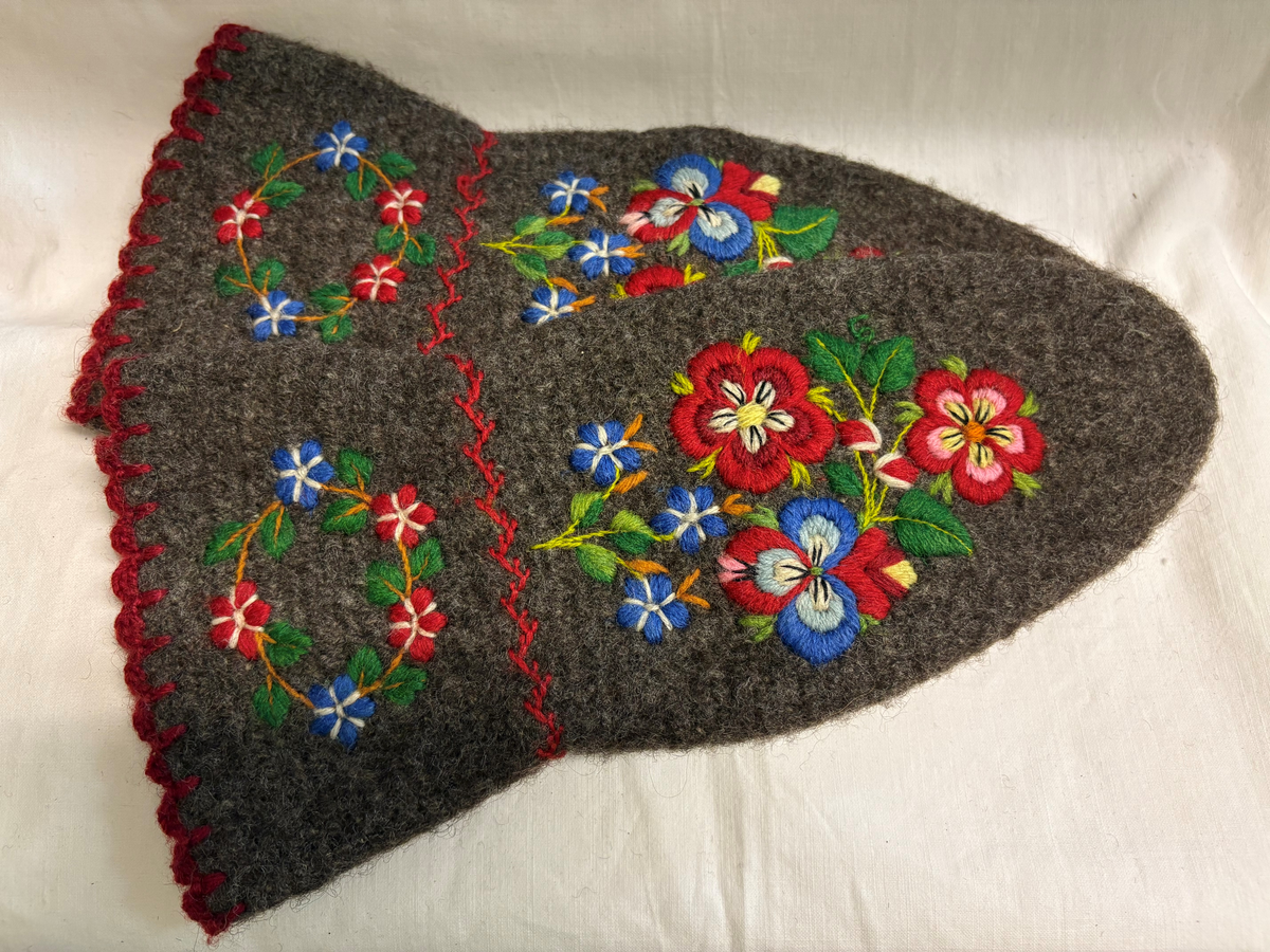 Tumvantar av brunt yllegarn. Broderi i rött, grönt, blått, rosa, gult och lila.