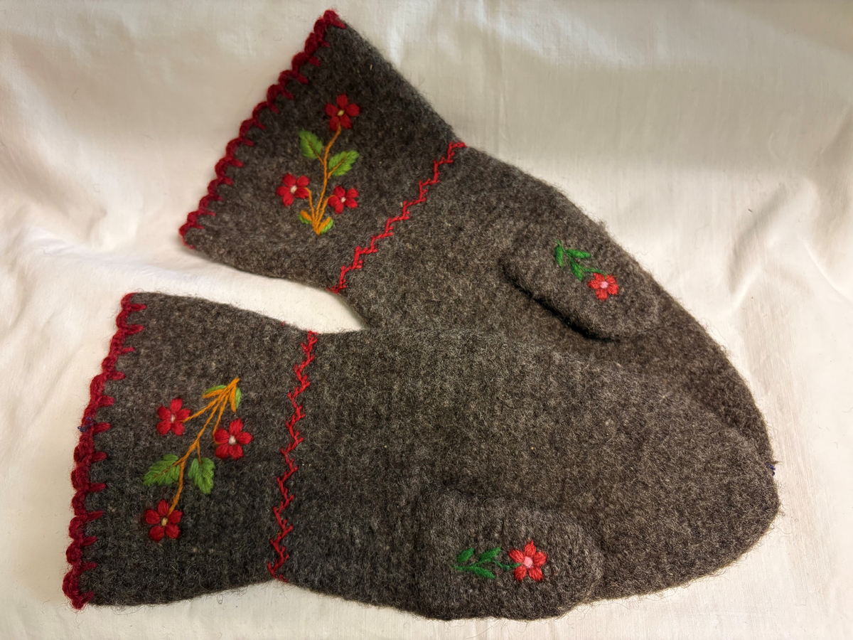Tumvantar av brunt yllegarn. Broderi i rött, grönt, blått, rosa, gult och lila.
