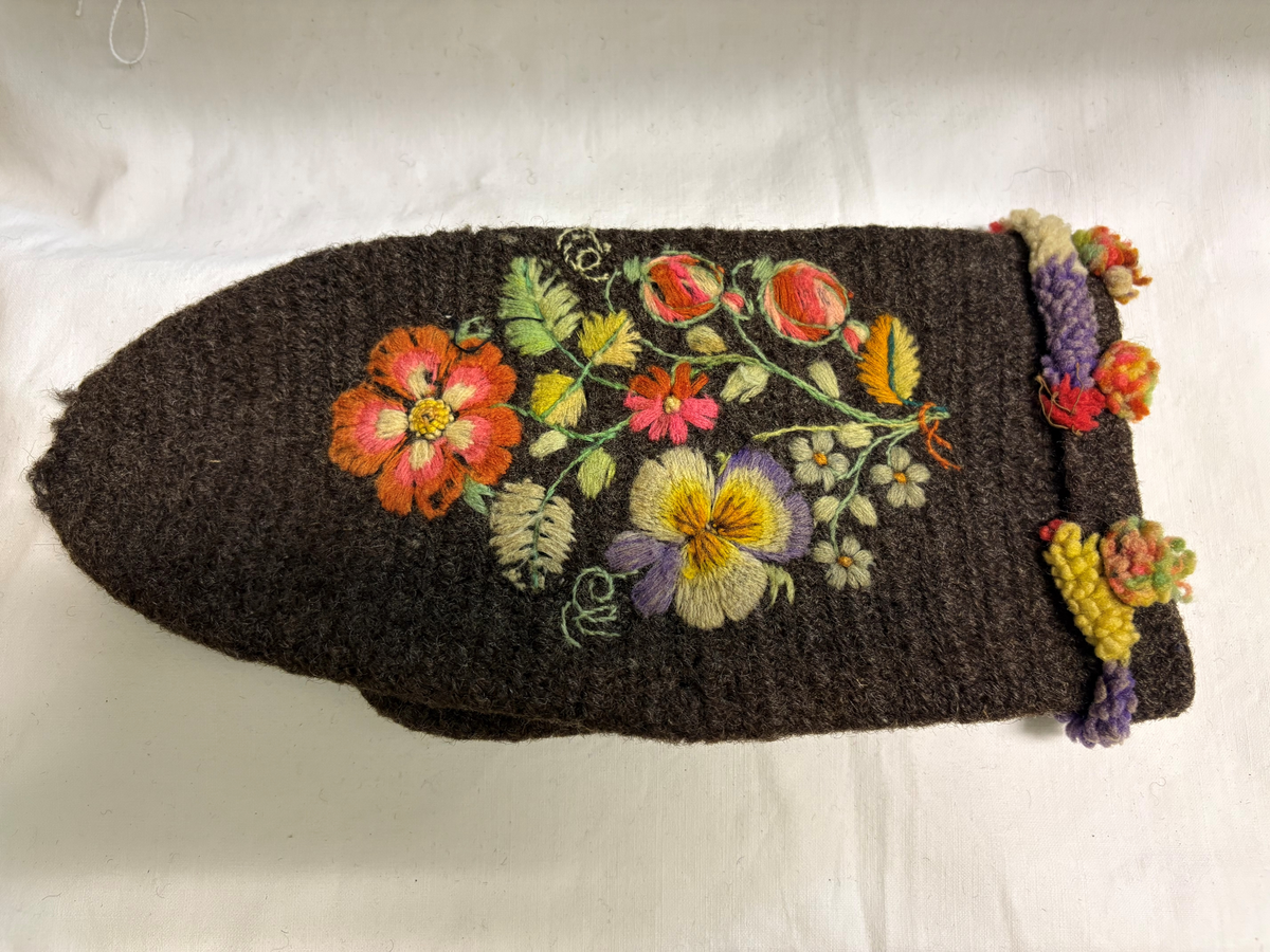 Brudgumsvantar, bruna. Broderade med yllegarn i färgerna lila, gult, grönt, vitt och blått i schattersöm och stjälksöm. Nedvikt kant.