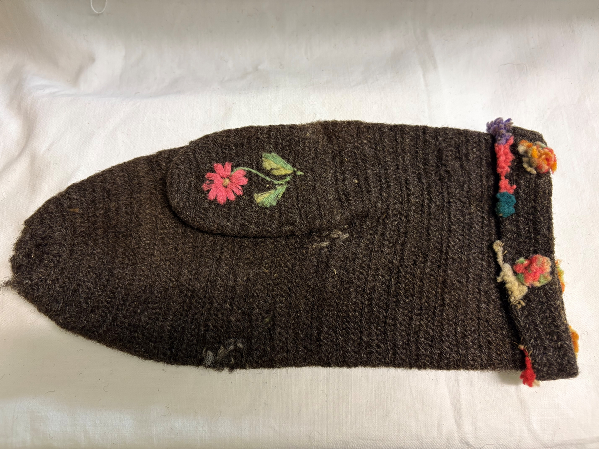 Brudgumsvantar, bruna. Broderade med yllegarn i färgerna lila, gult, grönt, vitt och blått i schattersöm och stjälksöm. Nedvikt kant.