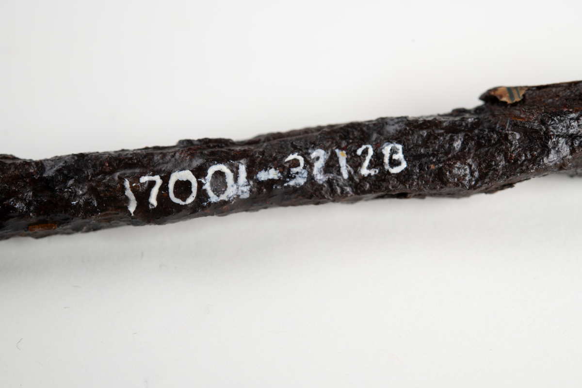 Långsmal rektangulär metallstång, vinklad nedåt i främre änden.
Märkt med plåtbricka nummer 25 som återfinns i katalog över Uddeholms Aktiebolags industrihistoriska samlingar, samt pappersetikett med text "Nordmarksbergs gruvor".