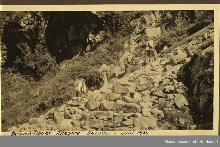 Arbeidarar transporterer sand i samanheng med påbygging av stemma på Salhusfjellet i juni 1923. Det vart lagd ein fem hundre meter lang røyrledning til vannreservoiret nedanfor der fabrikken fekk vassforsyninga si frå. Ledningen var av tre, og fekk mange lekkasjar ettersom åra gjekk. Den blei etter kvart skifta ut med galvaniserte jernrøyr.